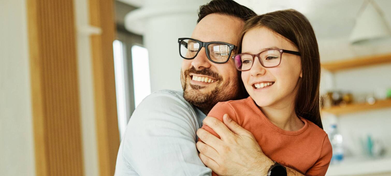 Dad tightly hugging daughter and smiling